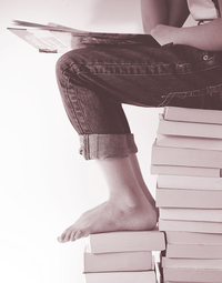 Foto einer Person, die auf einem Bücherstapel sitzt